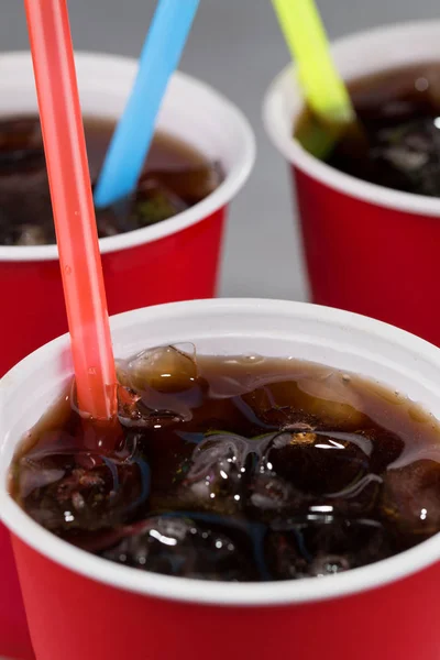 fizzy drink with ice in red cups with colored straws. closeup