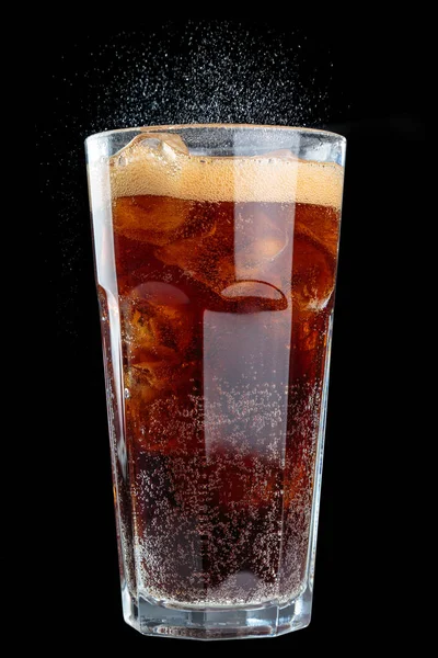 fizzy drink with ice in glass in studio, close up