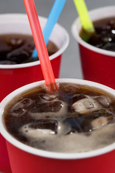 fizzy drink with ice in red cups with colored straws. closeup