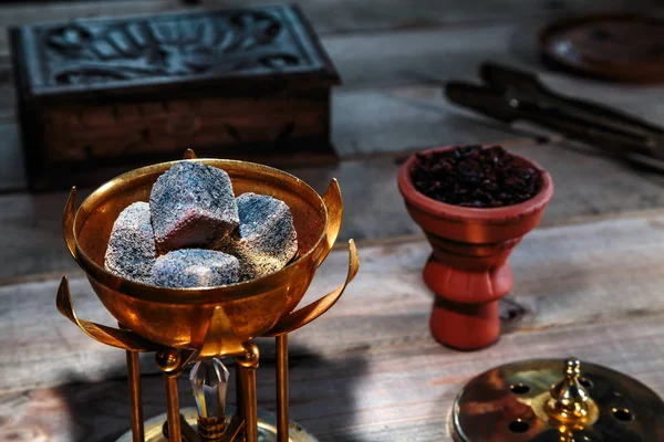 burning coals for Shisha Smoking are in the Golden bowl, made in the shape of a Lotus on the background of Smoking accessories