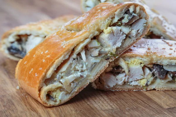 close-up shot of sliced pie stuffed with meat and vegetables on wooden table