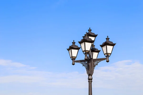 lamppost with antique lighting on blue sky background