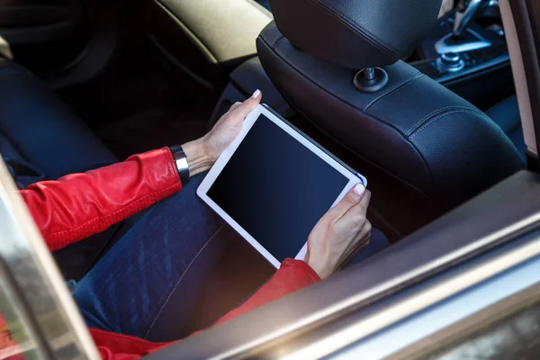 female hands with tablet on back seat of vehicle