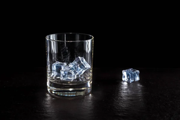 close-up shot of glass of whiskey and ice on black surface