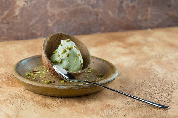 Homemade pistachio ice cream sprinkled with pistachio crumbs is served in half a coconut shell. Homemade pistachio sorbet.