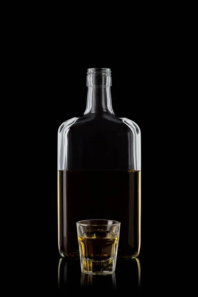 Bottle of whiskey and a glass of whiskey isolated on a black background with reflections. 100 sharpness. 100 sharpness. Vertical.