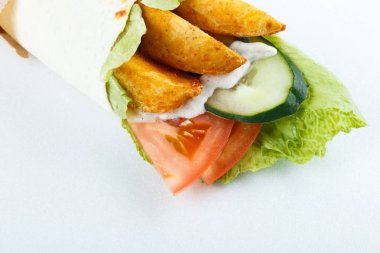 Lavaş ve humus kesme tahtası üzerinde bir kase patates ve sebze (salatalık, domates, salata) sarılı. Geleneksel Arap yemekleri. Yakın çekim görünümü.