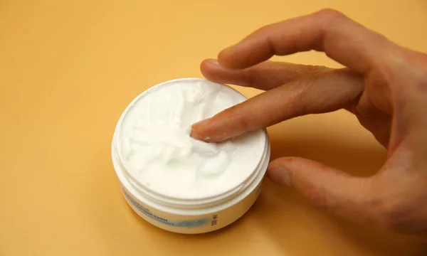 hand cream. A box of cream. Woman wants to smear hand cream. isolated yellow background