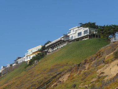 Yeşil tepelerdeki okyanus manzaralı evler mavi gökyüzü Kaliforniya kıyıları boyunca