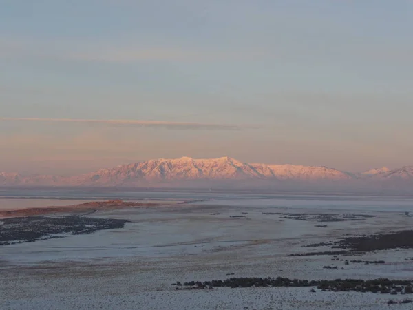 Utah 'taki Büyük Tuz Gölü boyunca uzak dağlarla kaplı karlı arazi manzarası.