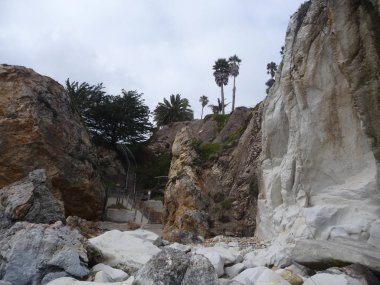 bulutlu gökyüzü altında tropikal yeşillik ile kayalar