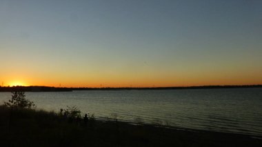 gün batımı gökyüzü altında uzak dağlar ile göl manzara