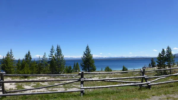 蓝天和远处的山脉在湖与绿色在围栏后面 — 图库照片