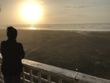 deniz üzerinde gün batımı bakarak kadın silüeti