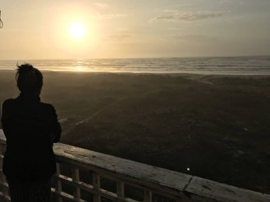 deniz üzerinde gün batımı bakarak kadın silüeti