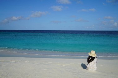 Dikiz deniz kumlu plajda otururken şapka giyen kadın