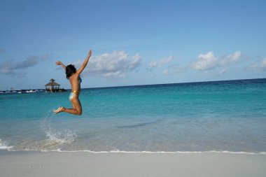 gün batımı ışığında sahilde atlama bikini kadın