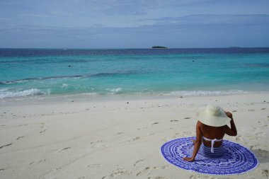 Dikiz kumsalda oturuyor şapka giyen kadın