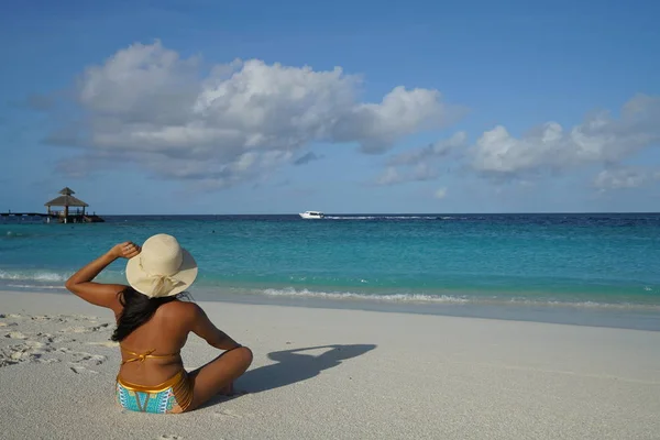 妇女戴帽子坐在沙滩上在阳光下 — 图库照片