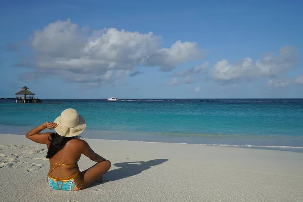 妇女戴帽子坐在沙滩上在阳光下 — 图库照片