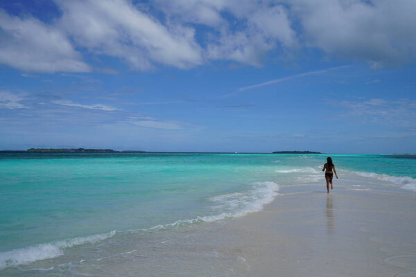rear view of woman wearing bikini running at blue bay