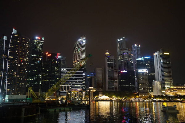 View of singapore harbor with skyscrapers illuminated at night