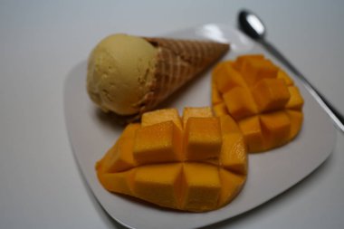 Mango aromalı dondurma koni tabağa dilimlenmiş mango ile