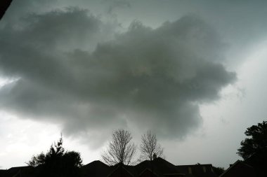 evlerin çatıları üzerinde çıplak ağaçlar ile dramatik bulutlu gökyüzü