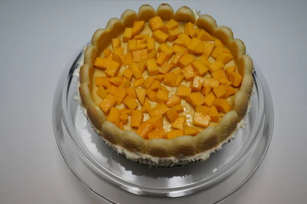 whole mango cheesecake on glass plate