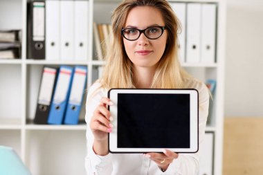 Güzel iş kadını giyen gözlük portre el gülümseyen ve kamera öğretmen arayan masadaki oturan bir tablet tutan ofisinde test kağıtları kontrol başarı ifade eder..