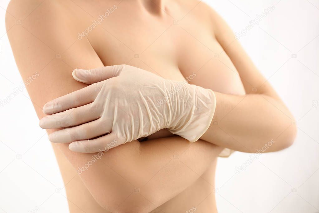 Female hand in gloves holding breast closeup