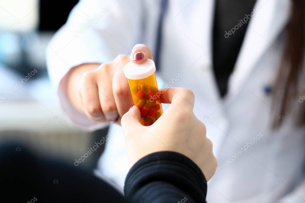 Female medicine doctor hand hold jar of pills and