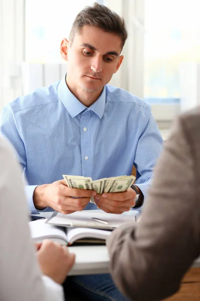 İşadamı nakit dolar ofiste inceliyor.