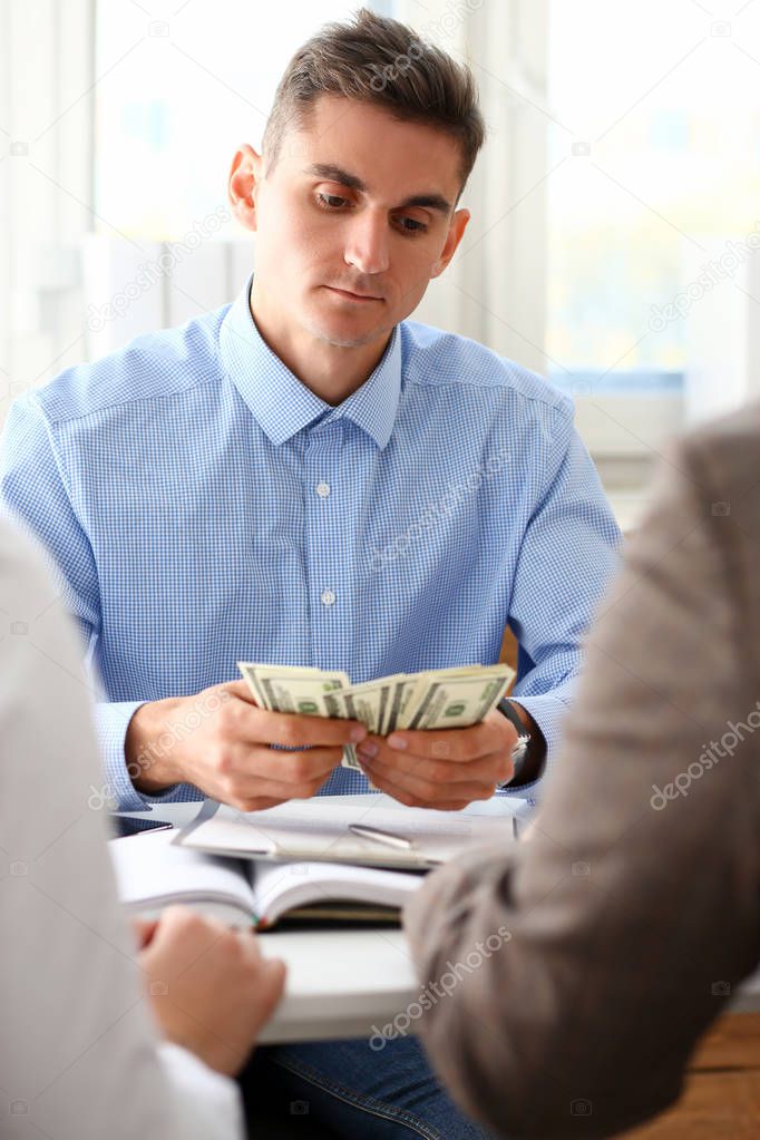 The businessman considers cash dollars in the office