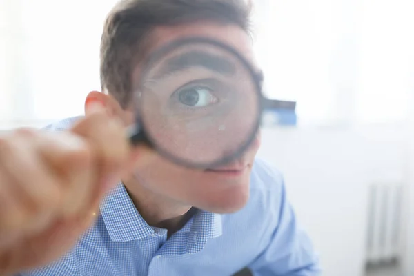 Mannen i kontorsarbete holding förstorande glas i handen — Stockfoto