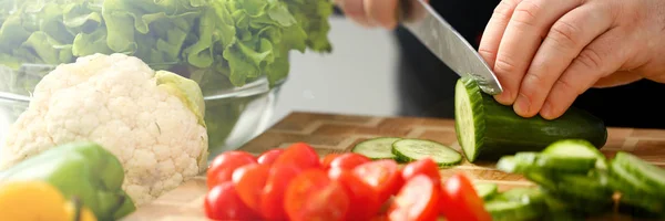 Cook holds knife in hand and cuts on