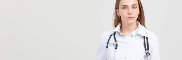 Lächelnde Ärztin mit Armkreuz-Porträt auf grau — Stockfoto