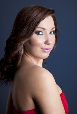 Mutlu, güzel, gülümseyen kadın portre. Moda ve güzellik stüdyoda vurdu. Karanlık, gri arka plan. Bir modeli kıvırcık saçlı ve koyu gölgeler makyaj.