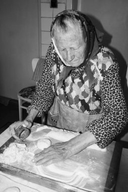 Happy, gülümseyen yaşlı kadın, bir büyükanne, kıdemli pişirme, rahat bir ev, mutfakta yemek. Orta Avrupa Kültür. Bir geleneksel giyen bir yaşlı kadın, slovak, Orta Avrupa kılık, kıyafet portresi. Retro, vintage tarzı.