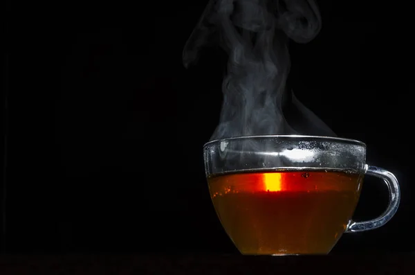 glass cup with tea infusion, on black background with label to write text