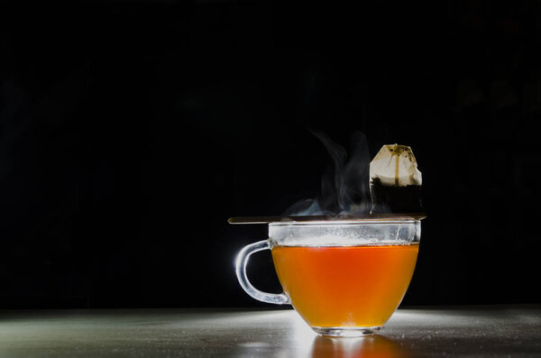glass cup with tea infusion, on black background with label to write text