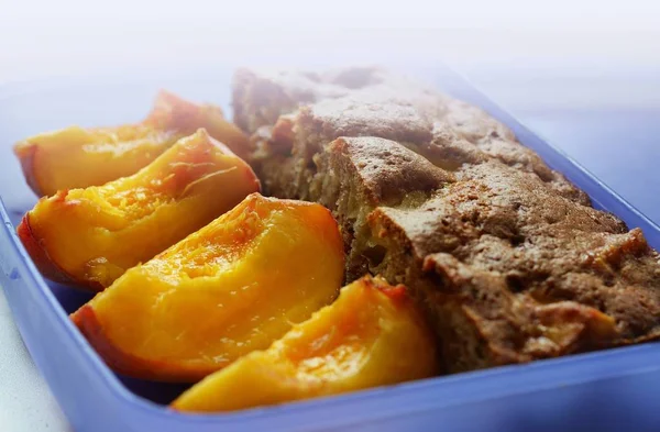 Piece of cake and sliced peaches on a plate.