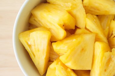 Ahşap bir masa yerleştirilen bir plaka üzerinde dilim ananas.