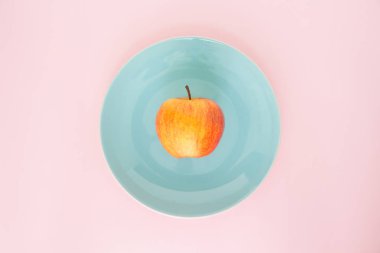 Mavi Plaka en iyi odak pembe bir arka plan üzerinde kırmızı elma