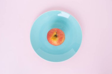 Mavi Plaka en iyi odak pembe bir arka plan üzerinde kırmızı elma