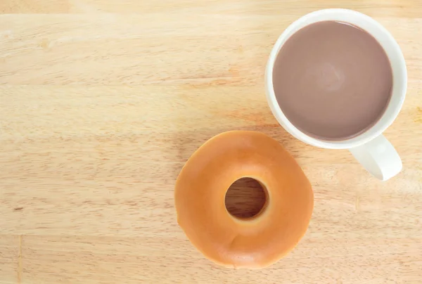 donut and cup cocoa drink top view on wooden background.