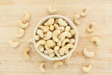 ahşap arka plan üzerinde beyaz kase üst görünümünde kaşu.