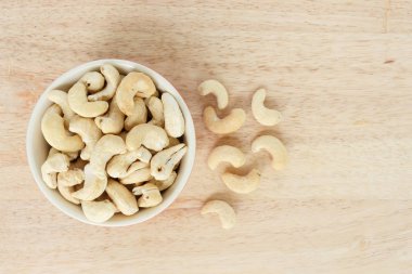 ahşap arka plan üzerinde beyaz kase üst görünümünde kaşu.