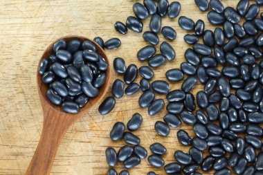 Tahta arka plan üzerinde kaşık siyah fasulye.