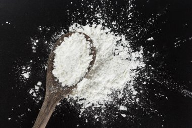 siyah arka plan üzerinde pişirme kaşık üzerinde beyaz un.